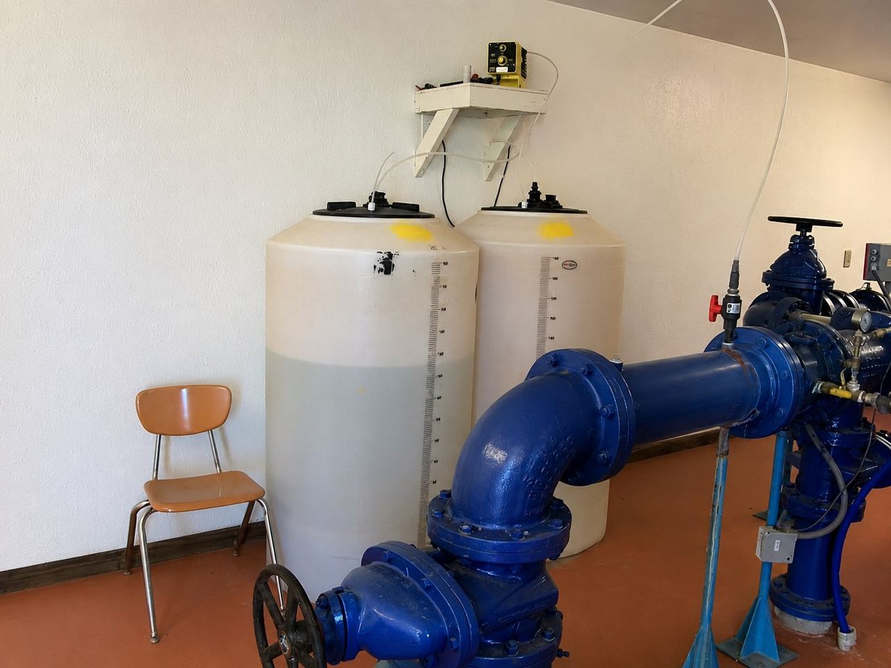 Booster pumps and white solution tanks in a water system pump room