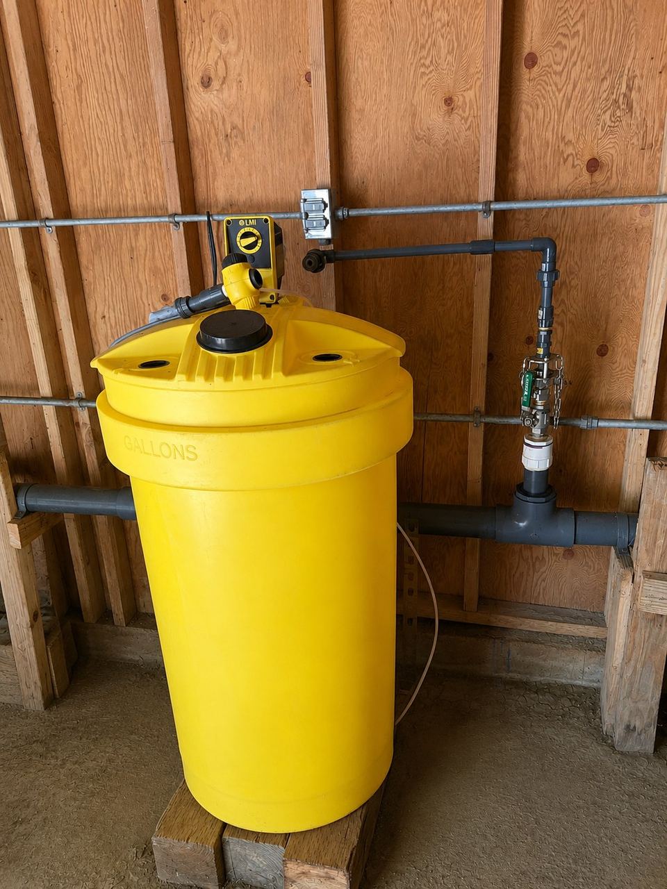 Chemical day tank and feed pump in a wood-framed pump house