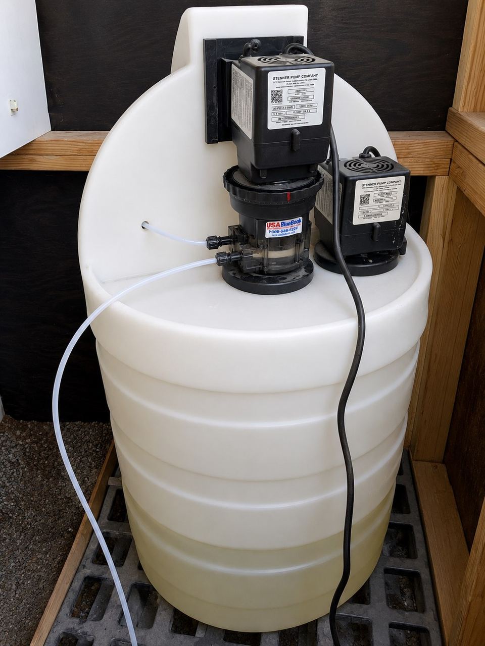 Two chemical metering pumps mounted on a white poly dosing tank