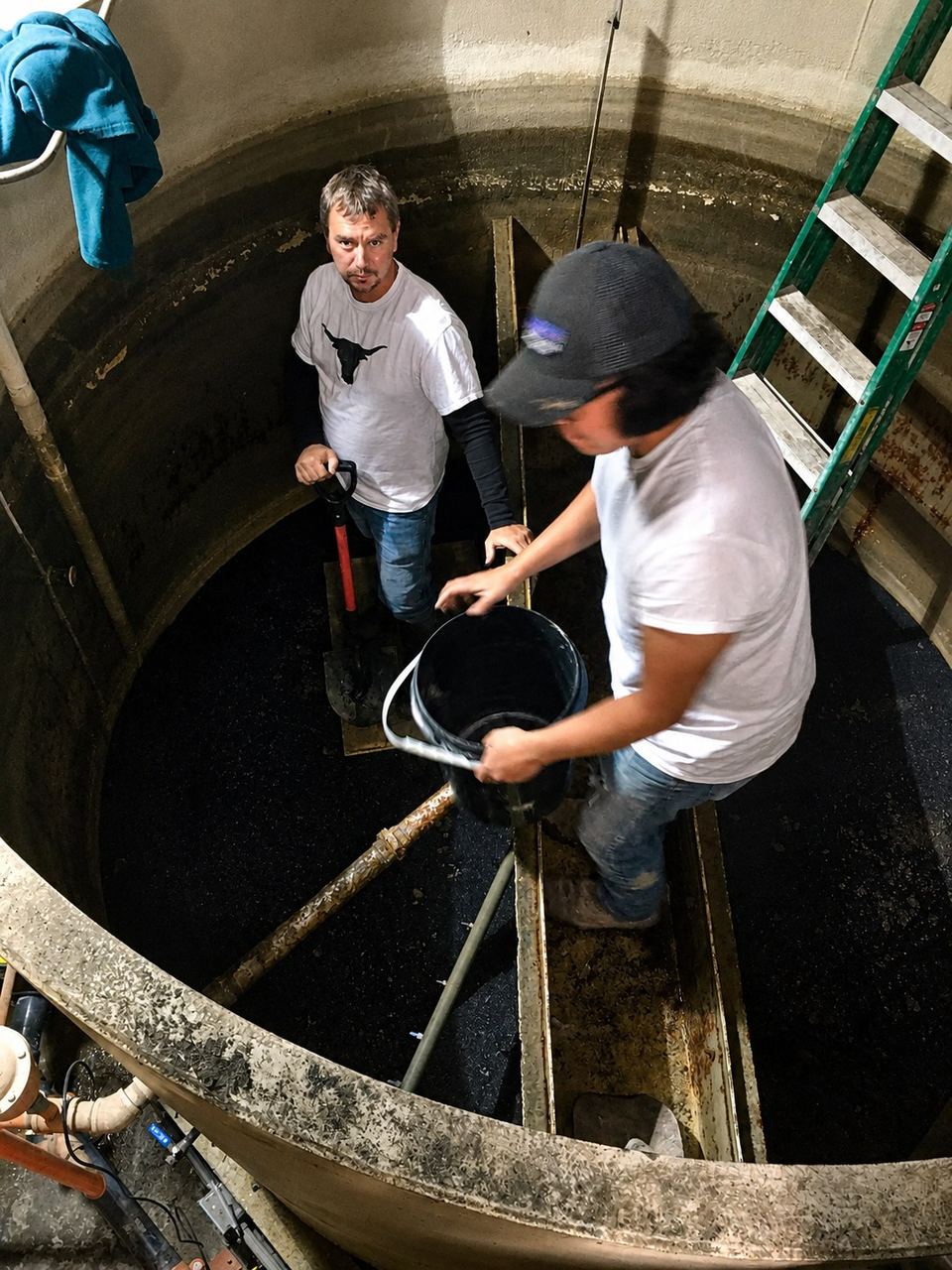 Two workers entering a concrete wet well during a confined-space entry