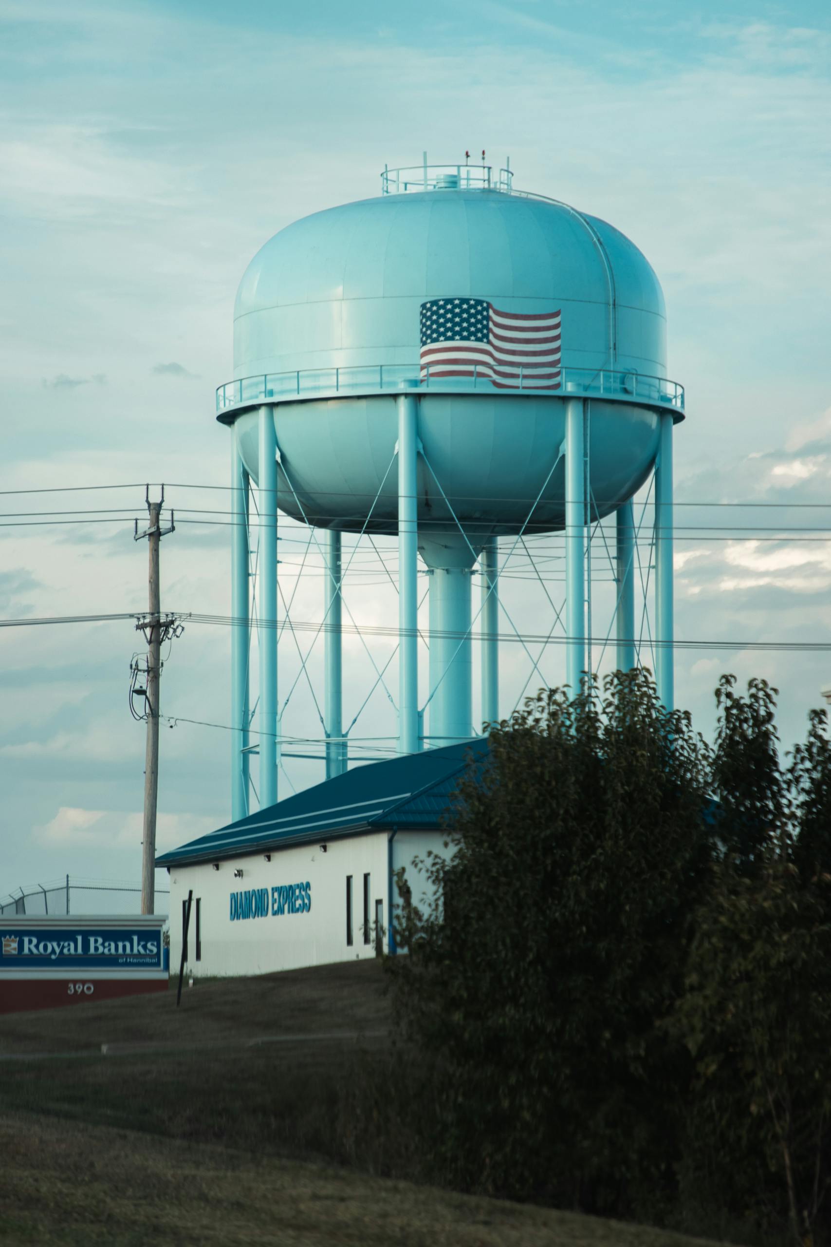 Blue water storage tower with American flag in a rural landscape