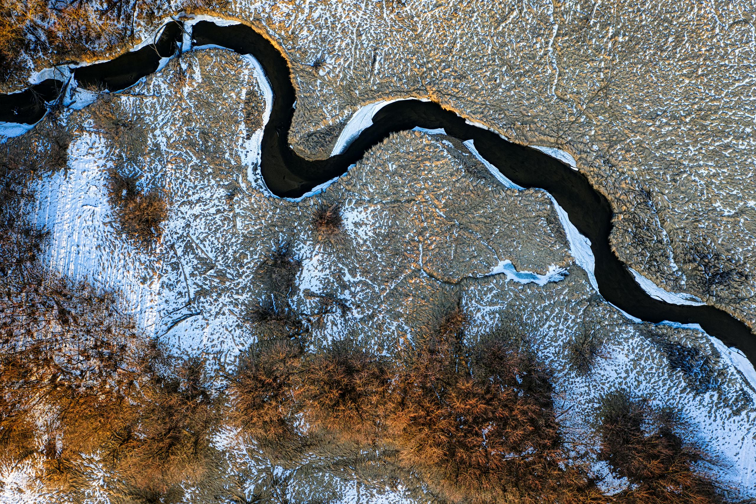 Aerial view of a winding river through snowy Minnesota fields in winter