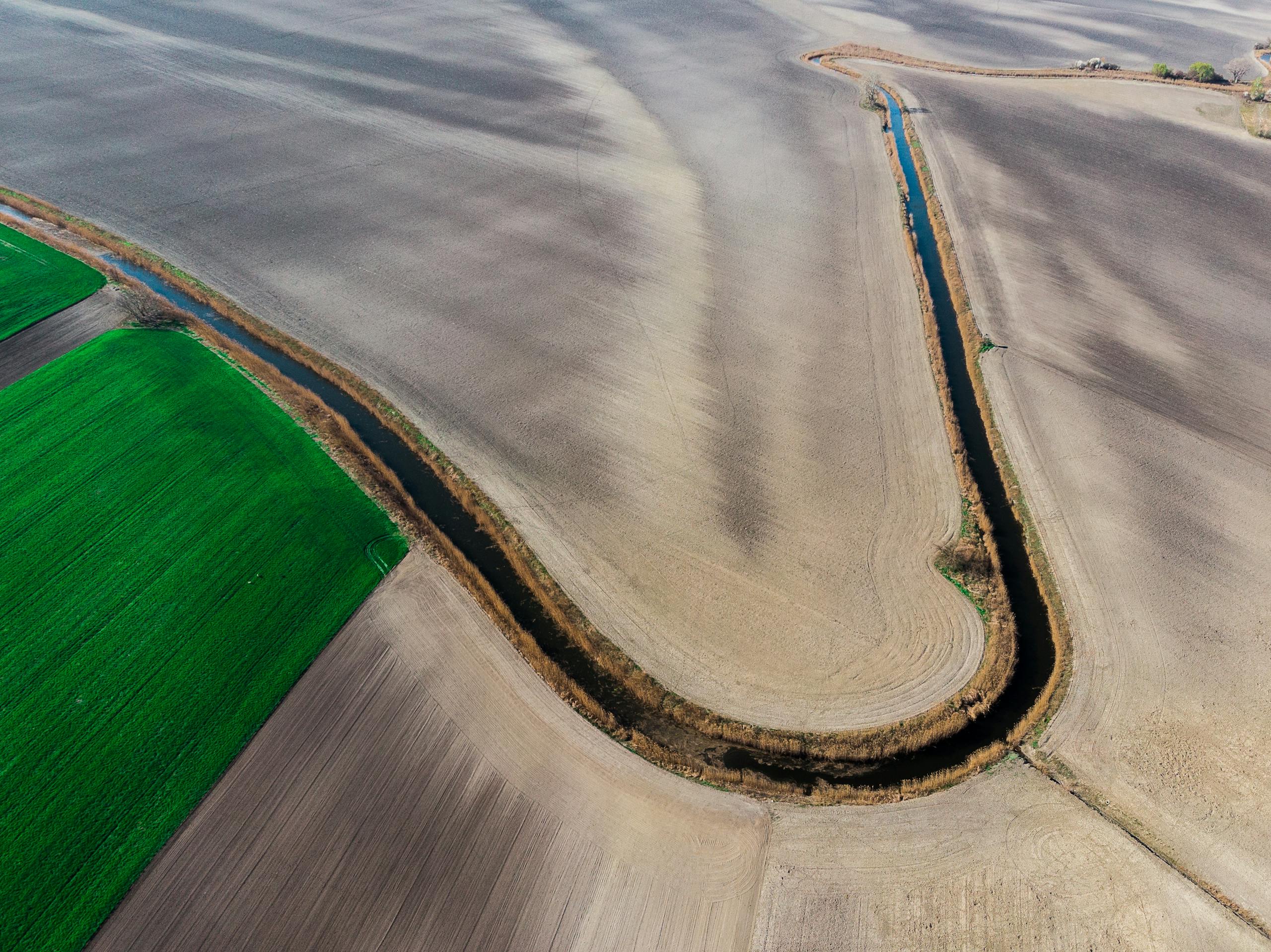 Aerial view of agricultural fields and a winding waterway representing distribution system flushing